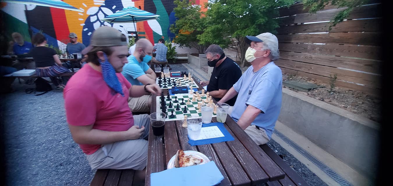 A group of Ruston chess players engaged in chess outside.